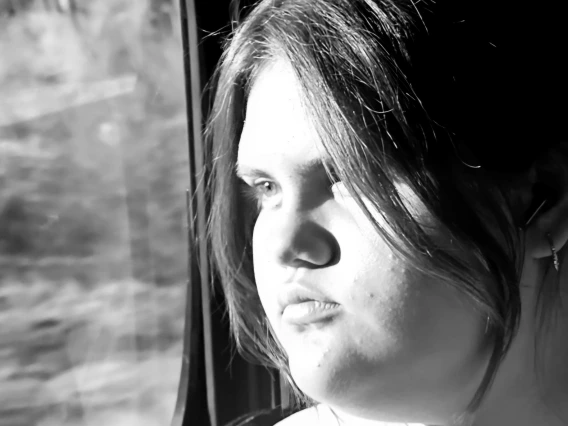 a black and white photo of a person looking out a window